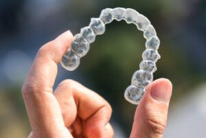 Holding,Invisalign,Braces,On,Bokeh,Background